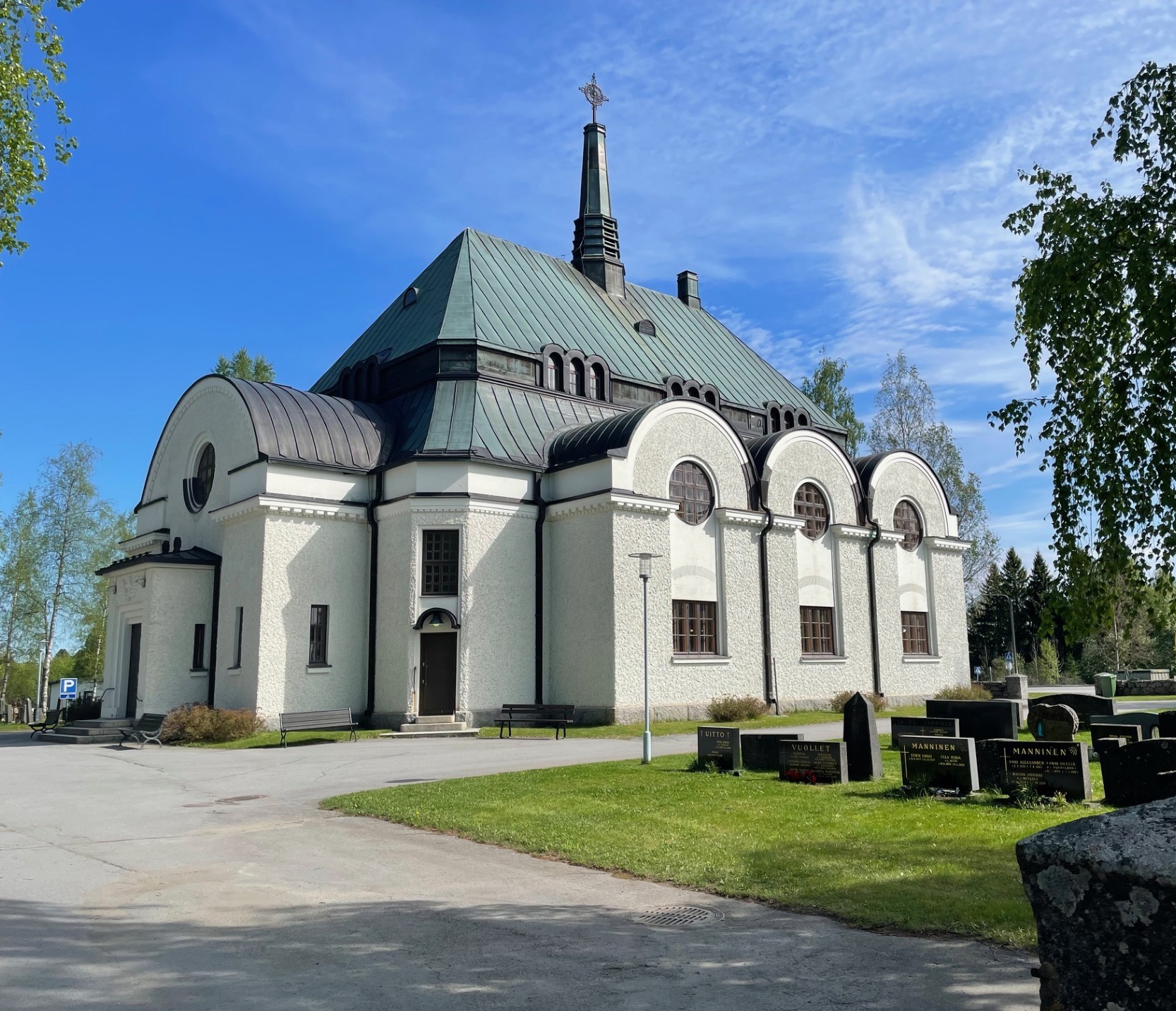 Valkoinen kivikirkko kesämaisemassa.