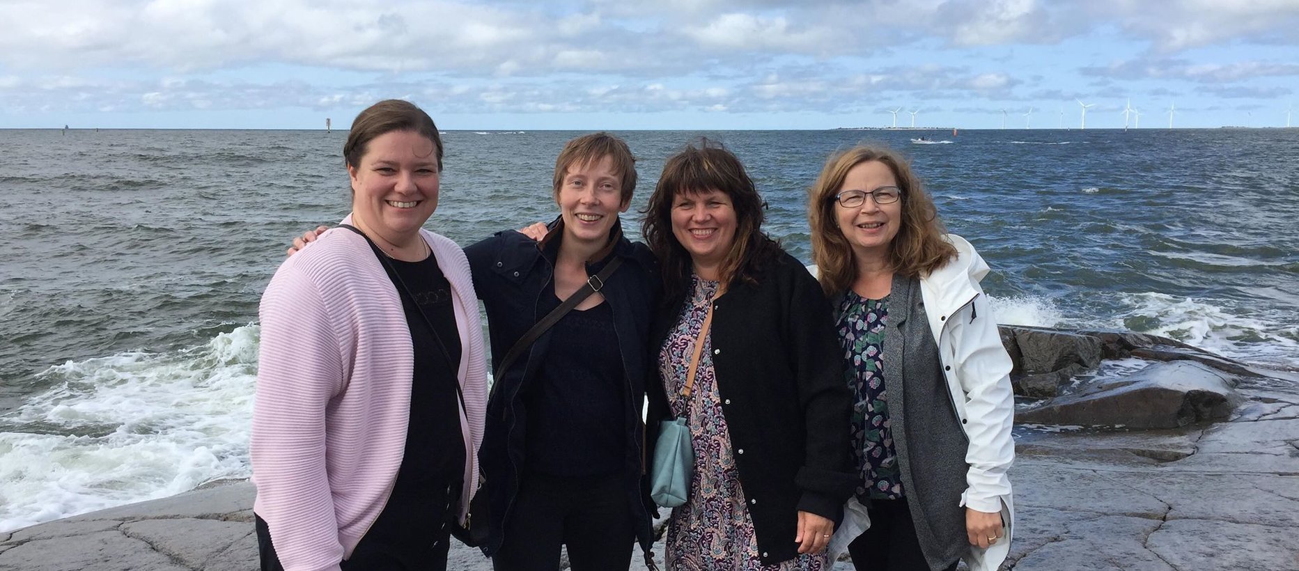 4 naista meren rannalla vieretysten.